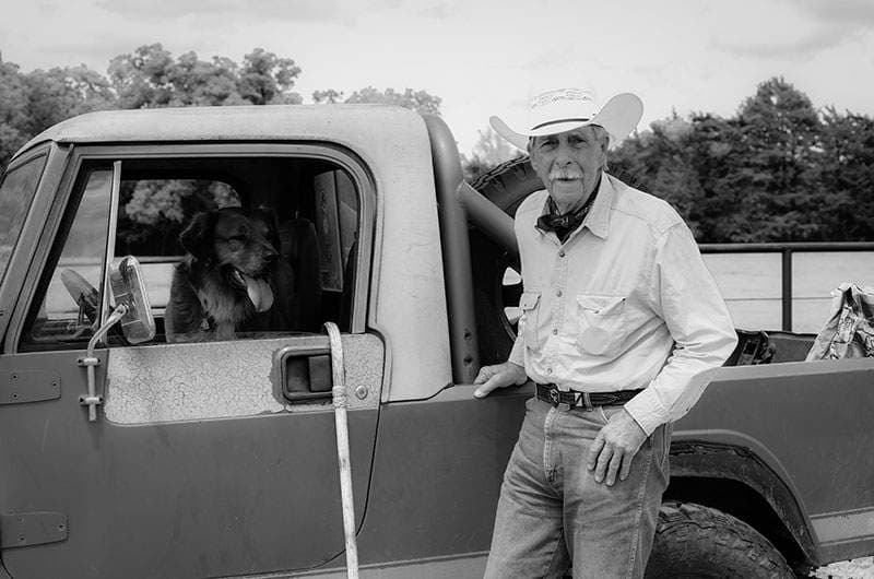 Black-and-white cowboy leaning on a vintage truck — Greenville TX Western photography by BK Bennett