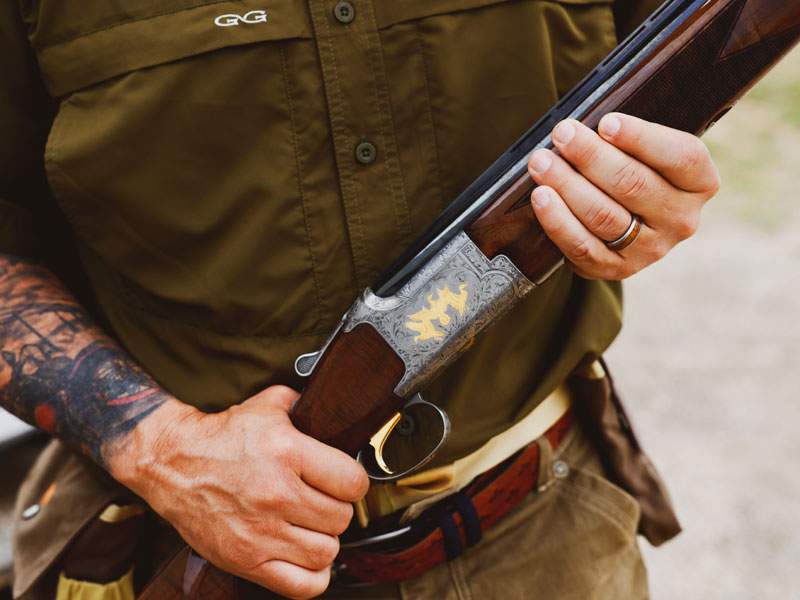 Close-up of a sportsman holding an engraved over-under shotgun with gold inlay — Texas hunting and outdoor lifestyle session