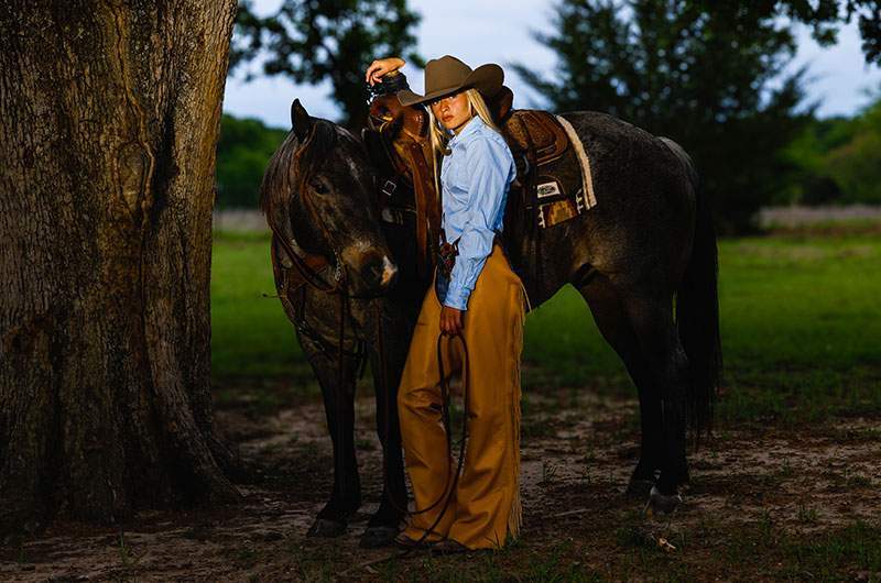 Senior in a cowboy hat beside a blue roan horse at dusk — Rockwall senior photographer BK Bennett