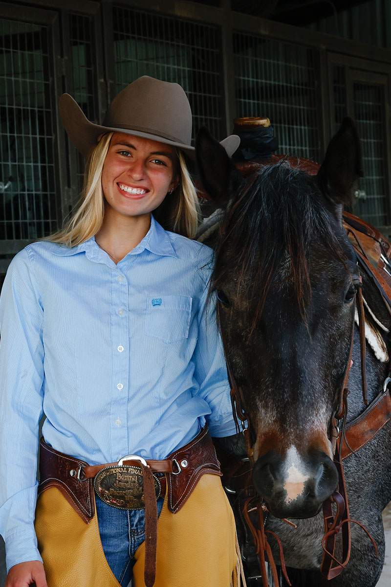 Senior in a cowboy hat beside a horse in a stable — McKinney senior portraits by BK Bennett
