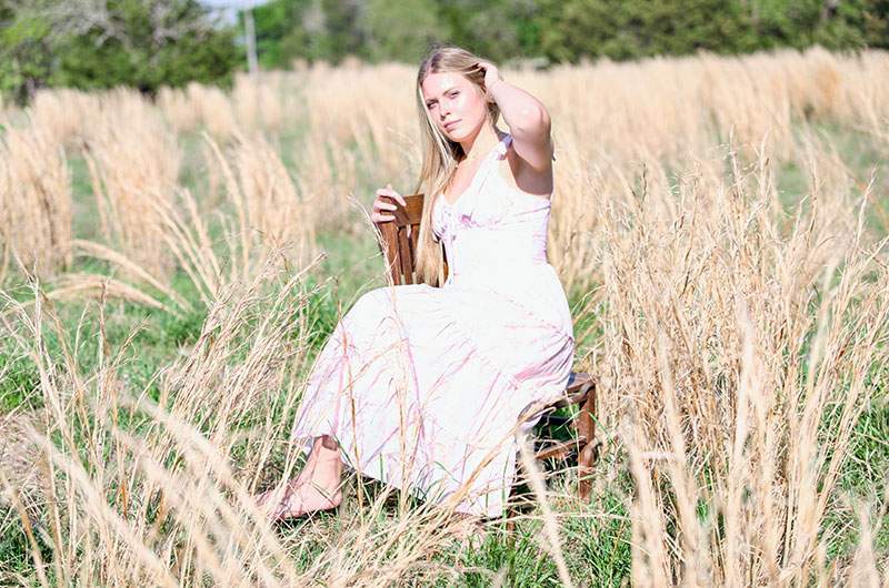 Senior in a white floral dress seated in a golden pasture — Plano senior portraits by BK Bennett
