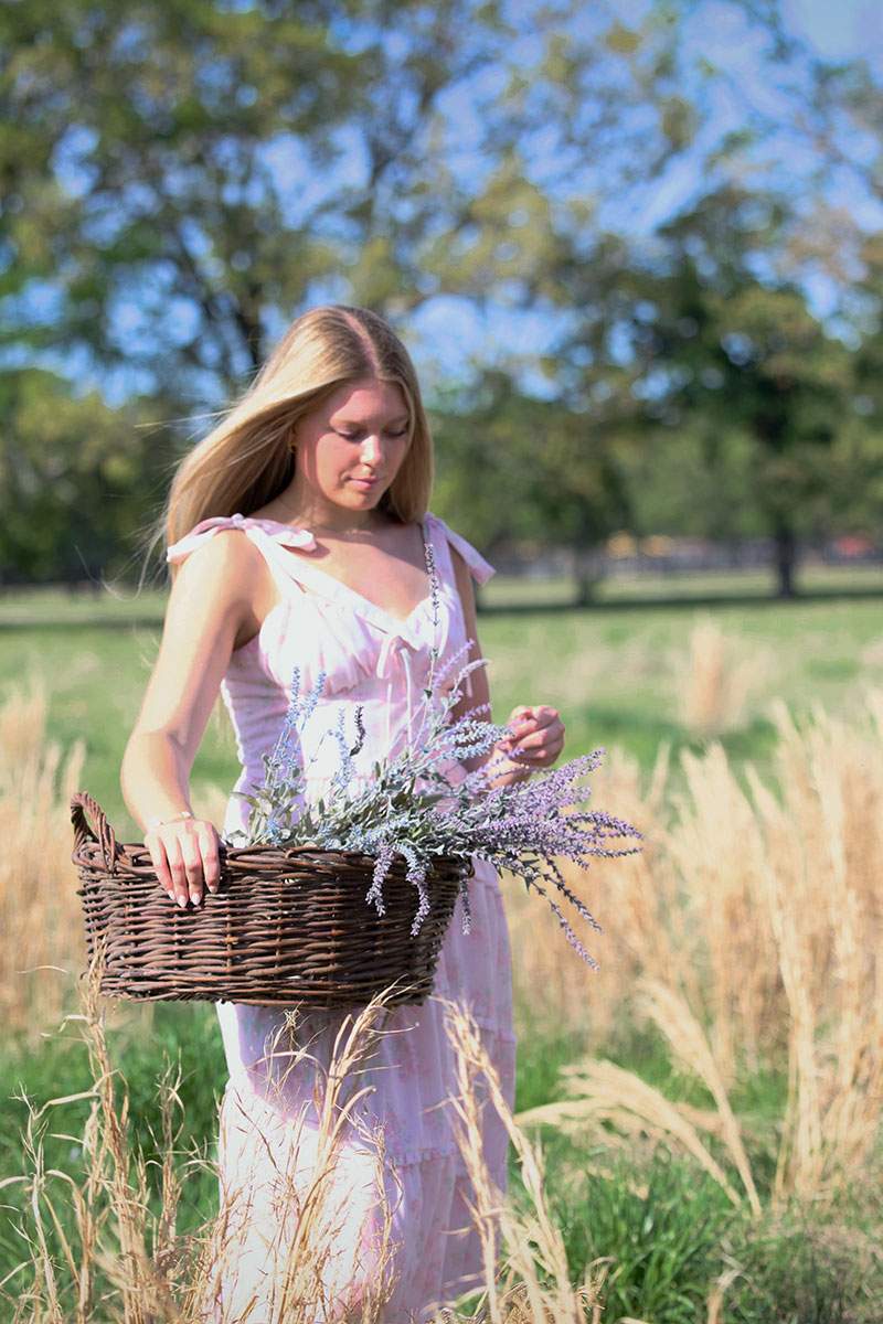 Senior in a pink dress carrying lavender through a sunlit field — Frisco senior photographer BK Bennett